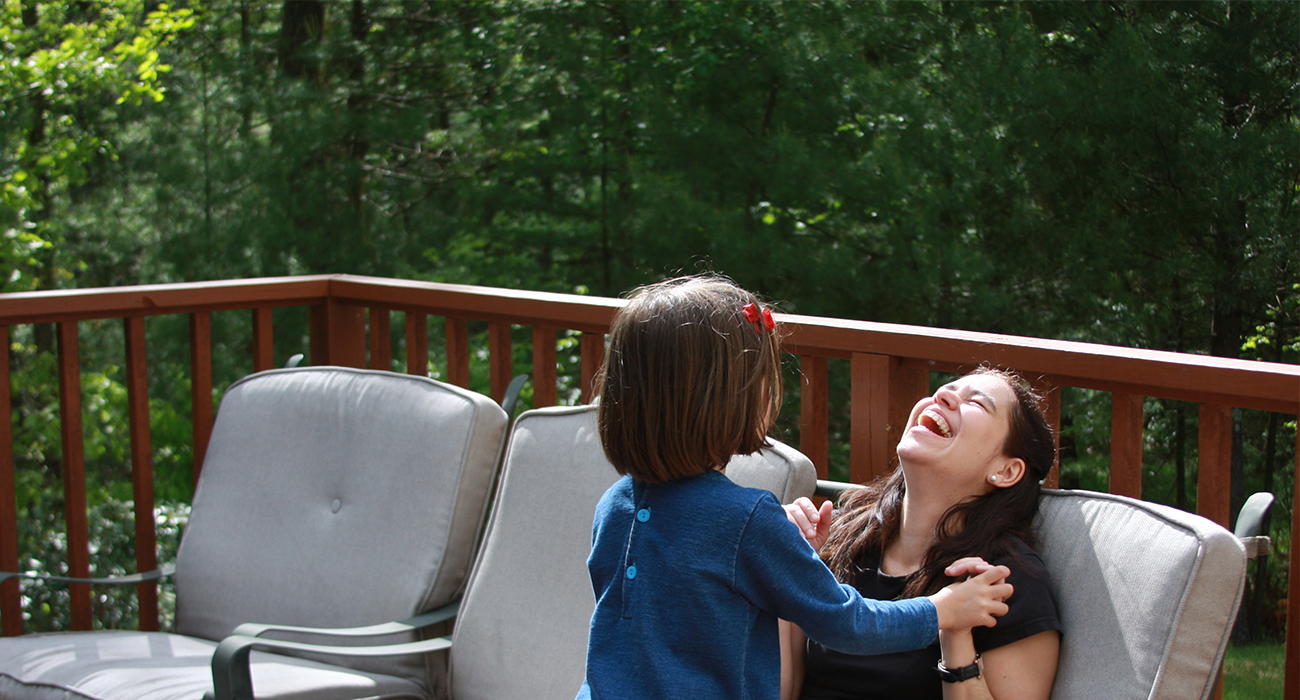 mom and daughter laughing on the back yard deck