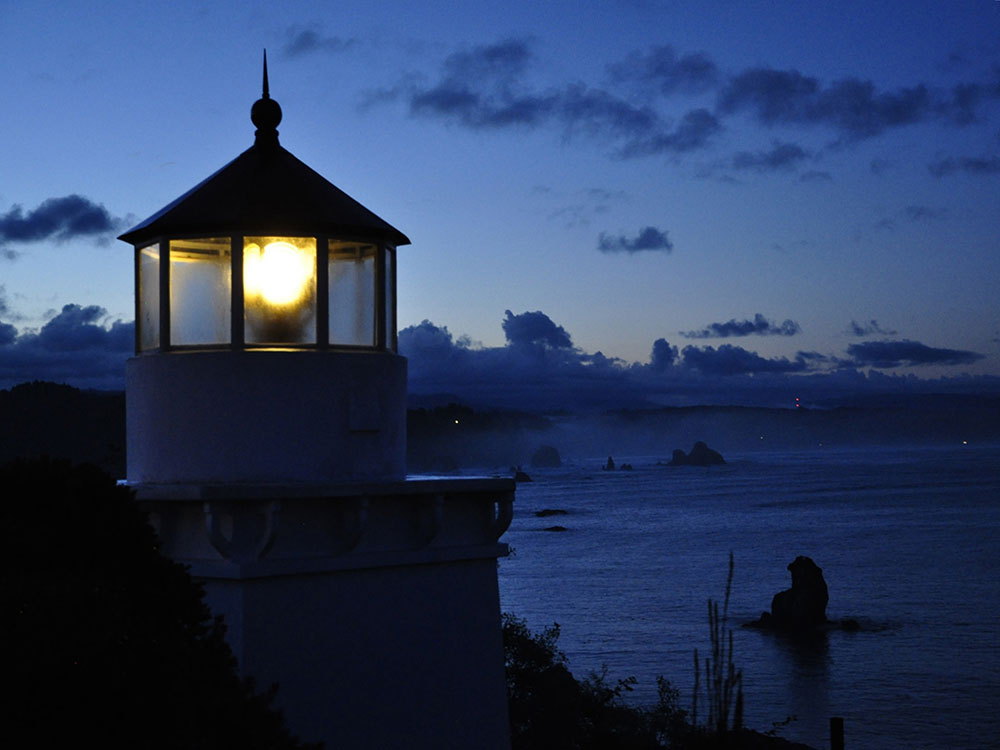 close up of a light house lighting the dawn of a coast