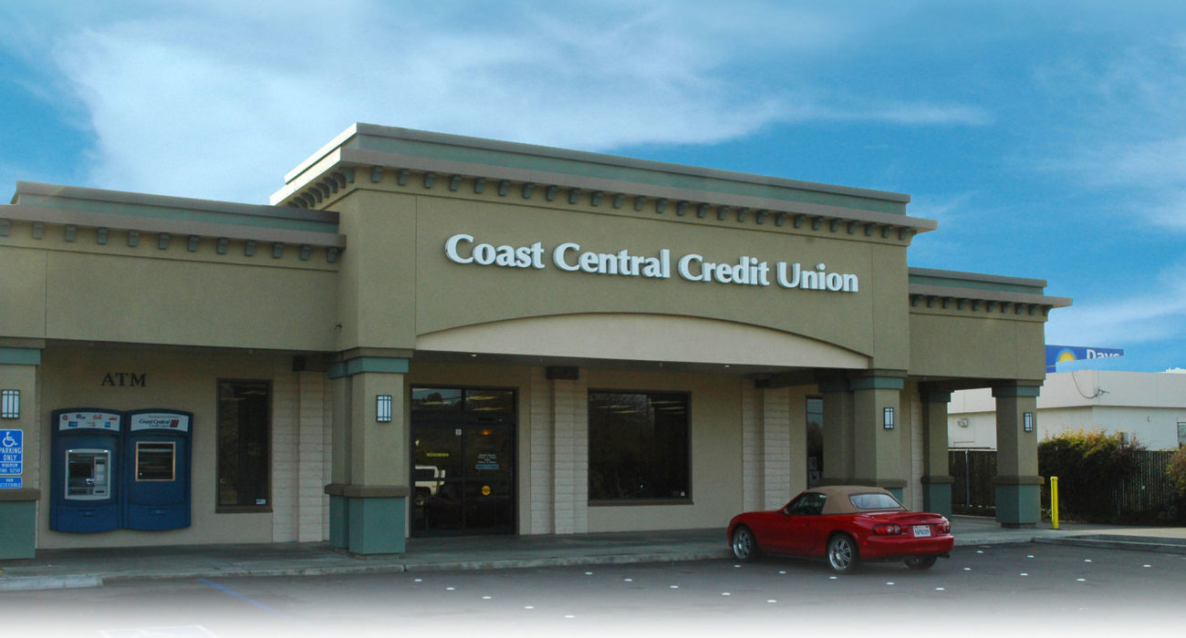 credit union building with red car parked out front and blue skies