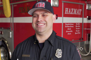 smiling man in front of emergency vehicle