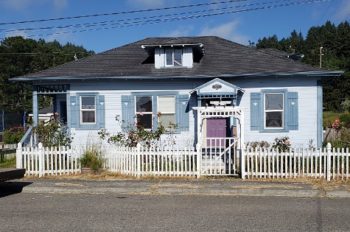 Blue trimmed house with a white picket fence.