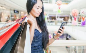 Young woman shopping looks at her phone. Let our CCCU Control App give you added security!