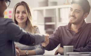 Young couple shaking hands with an agent. We're happy to help you plan your financial future!