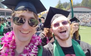 Two Humboldt State University students smile during their graduation.