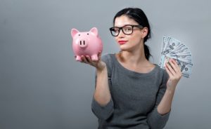 Young woman holding up a piggy bank with US 100 dollar bills.