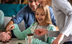 Parents help their teens learn to save with a piggy bank.