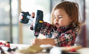 2 year old girl holds carpenter tools above a table. We'll help you finance your home improvement projects.