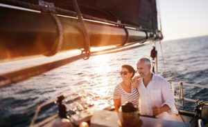 Happy couple boating on ocean with sun setting. We'll help you achieve the awesome retirement you deserve.