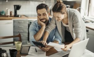 Young couple reviewing their finances on a tablet. Our personal financial management system, MoneyMaster, will help you save for a better tomorrow.
