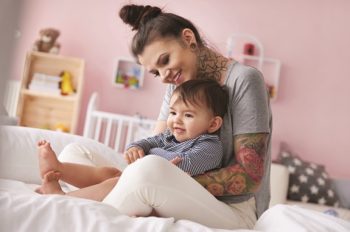Young mother holds her toddler son on her lap