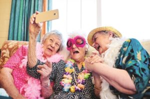 Three elderly women smile and laugh while taking a selfie