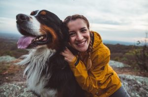 Young lady sits smiles alongside her happy dog