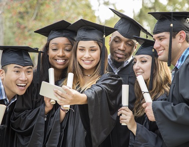Group of college students take a smiling selfie together after graduation