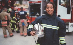 Firefighter with work helmet under arm smiling at camera