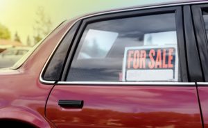 Shiny red car with a for sale sign