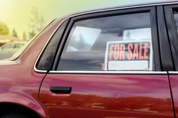 Shiny red car with a for sale sign
