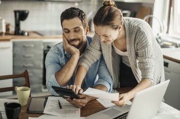 Young couple reviewing their finances on a tablet. Our personal financial management system, MoneyMaster, will help you save for a better tomorrow.