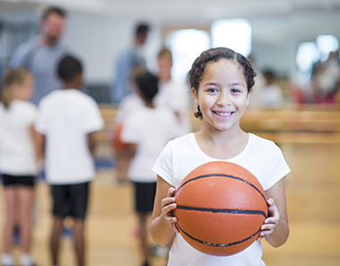 Photo of a group of kids playing basketball indoors