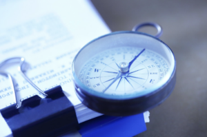 A compass on top of a pile of papers