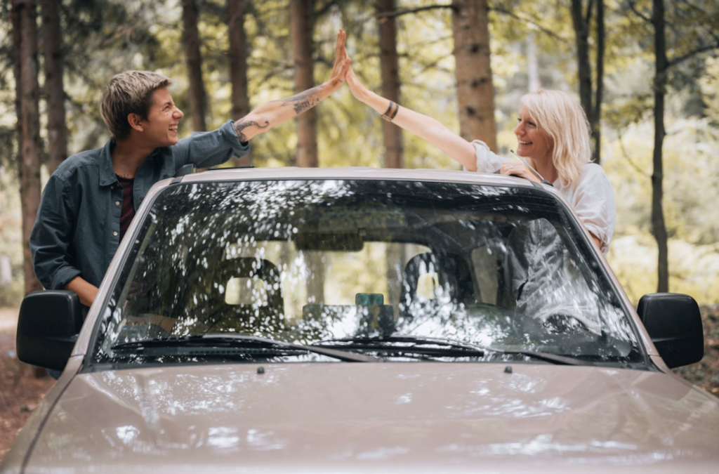 Two people popping their heads out of a car window