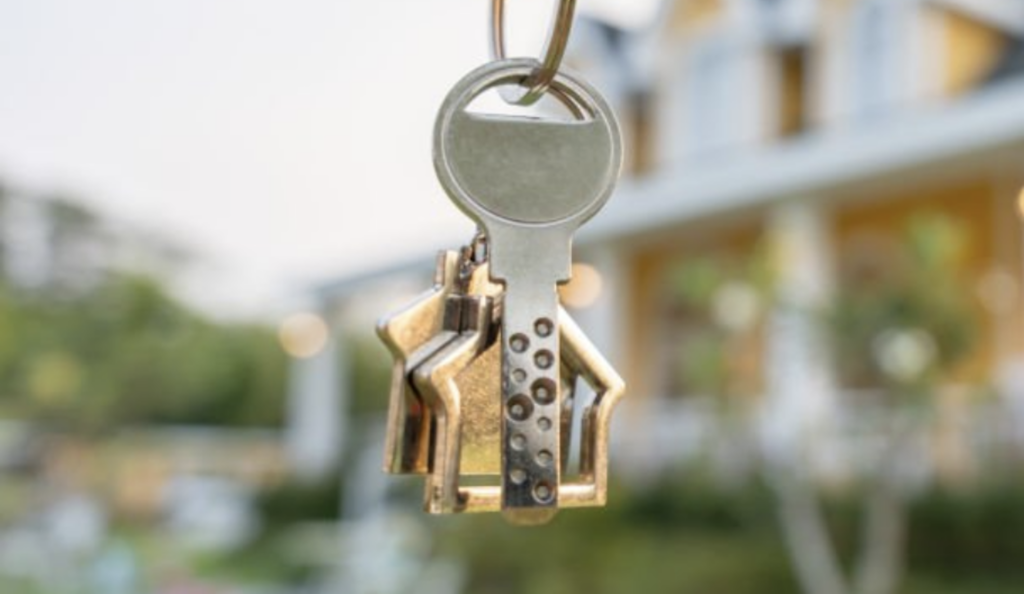 Homeowner holding the keys to the house infront of their home