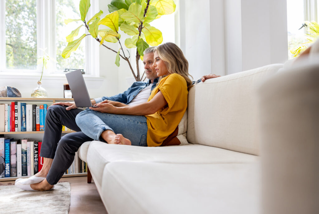 A couple sitting on a couch looking at a computer
