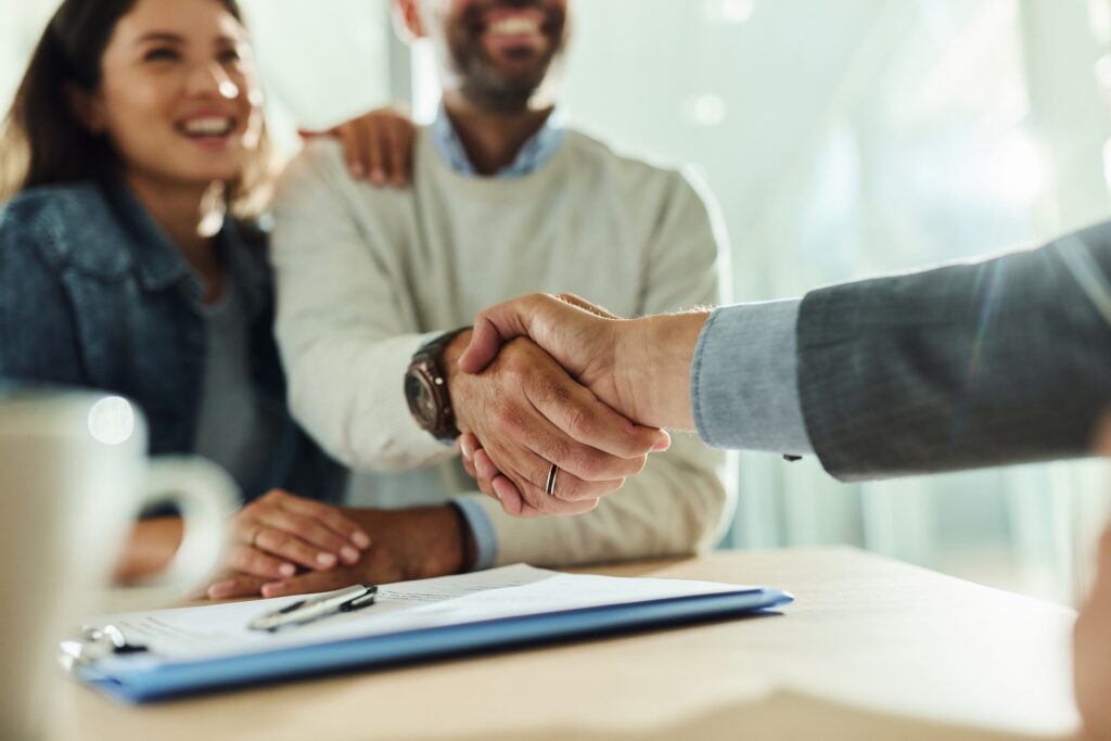 A couple sitting with the man shaking someones hand