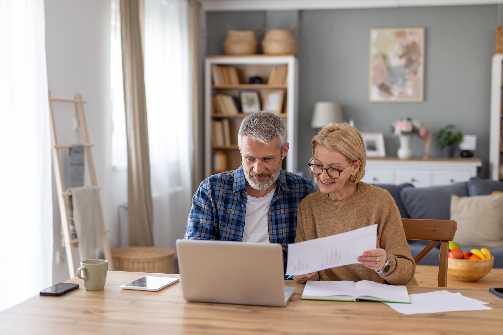 An elderly couple sitting and working on a laptop